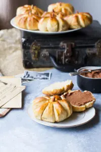 Pumpkin roll on a white plate on top of a black vintage suitcase.