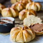 Pumpkin shaped roll with more blurred in the background.