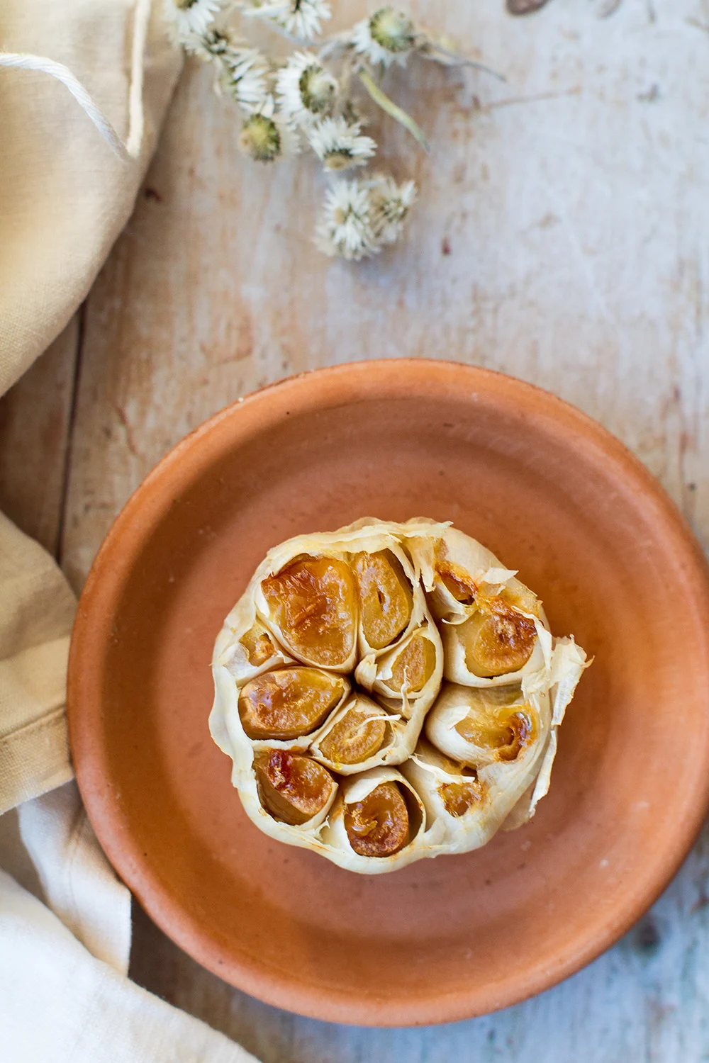 Roasted garlic on a small terracotta plate.