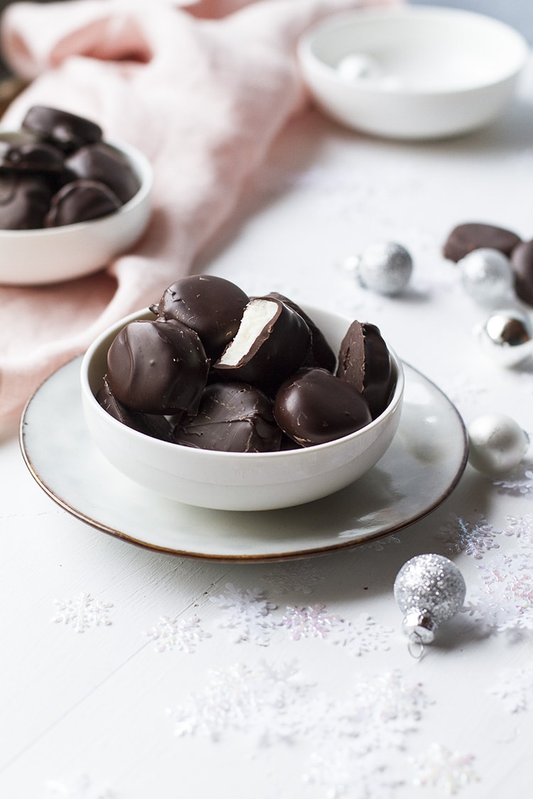 Small white bowl with peppermint patties on a white plate. Decorated with snow flakes and ornaments.