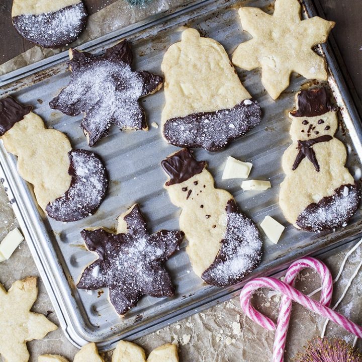Snowmen shaped and star shaped cookies on a cookie tray. Candy cane decorations. Flat-lay.