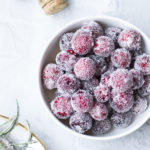 A white bowl with sugar frosted cranberries, seen from above.