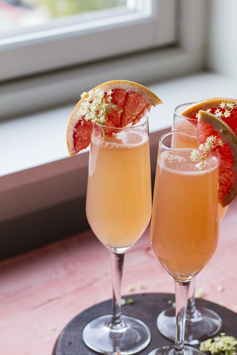 Three grapefruit cocktails in champagne flutes.