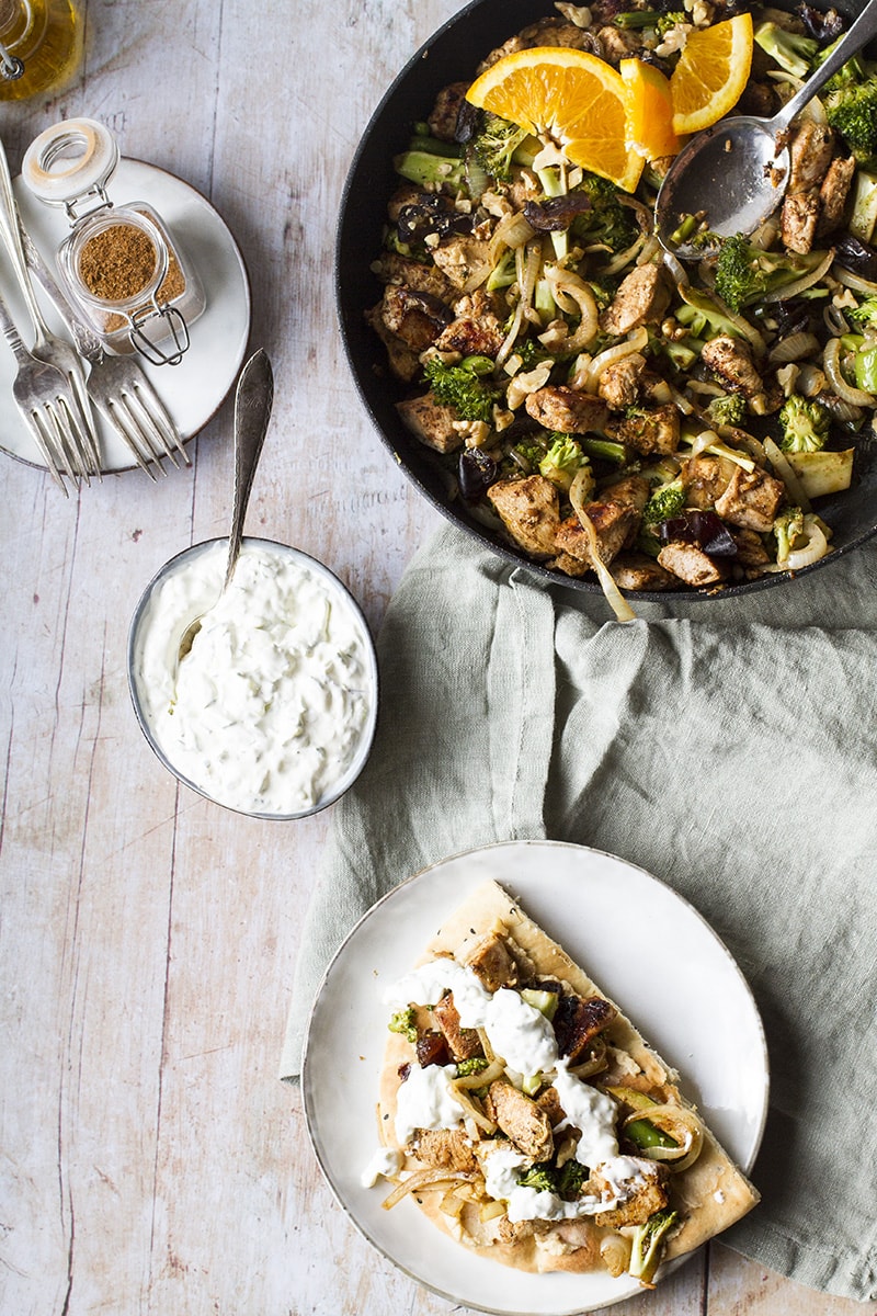A skillet with shawarma chicken and a plate with a naan and the chicken on top.