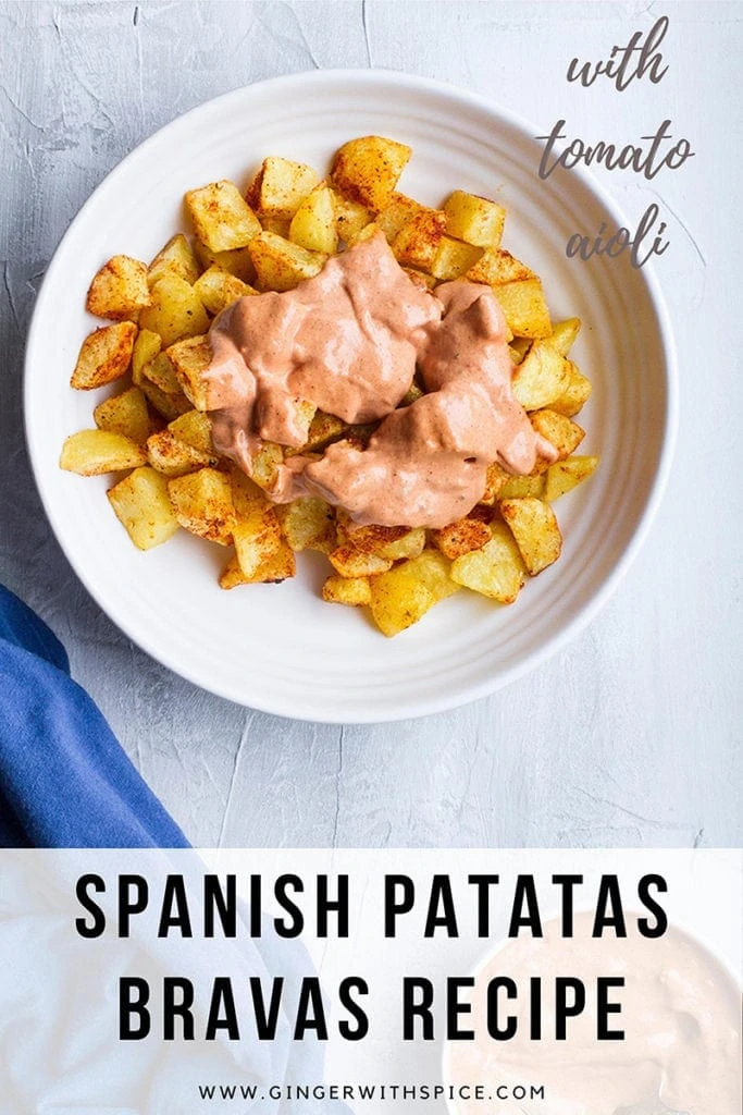Patatas bravas with salsa brava in a wide white dish. Pinterest pin with text at the bottom.