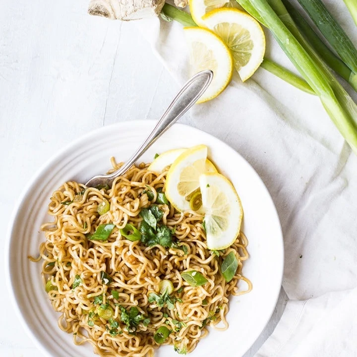 White bowl with fried noodles and green onion. Flatlay.
