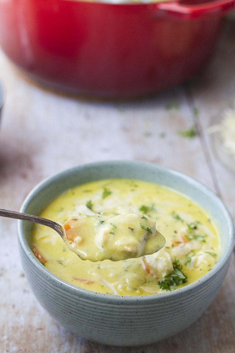 A spoon with creamy turmeric vegetable soup.