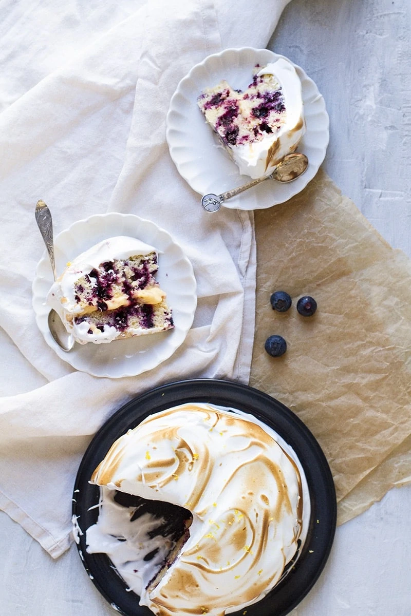 Two slices with blueberry cake and the whole cake on the side. Flatlay.