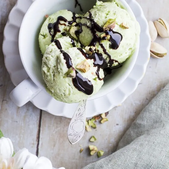 Pistachio ice cream in a cup, topped with chocolate sauce.