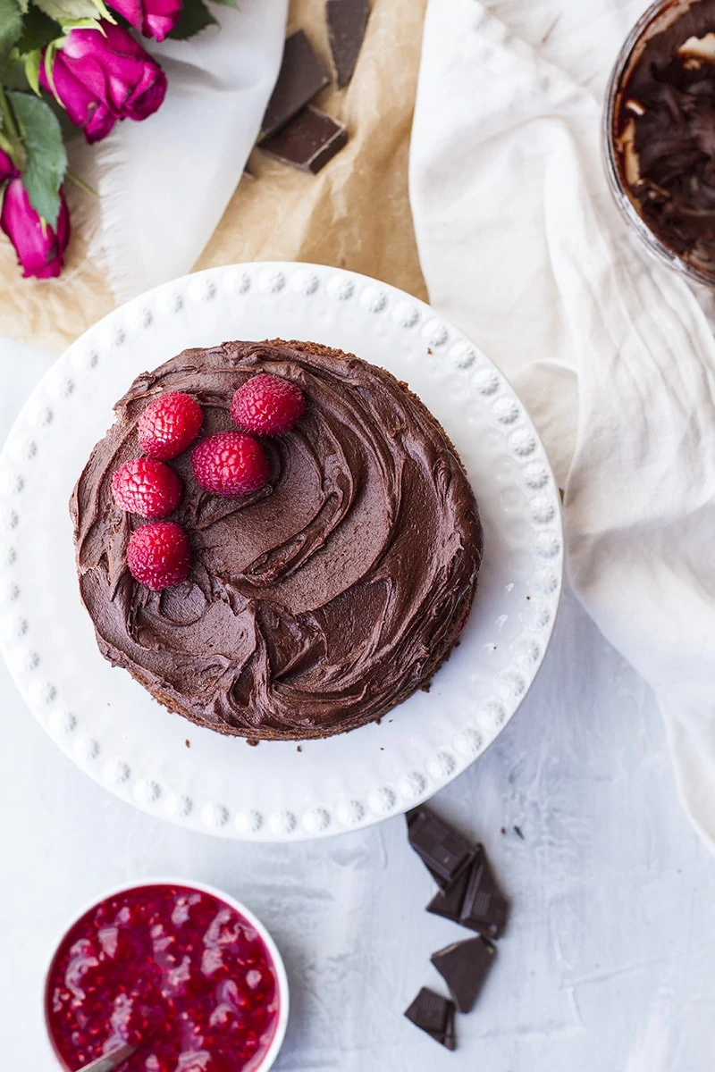 Raspberry chocolate cake on a white cake stand.