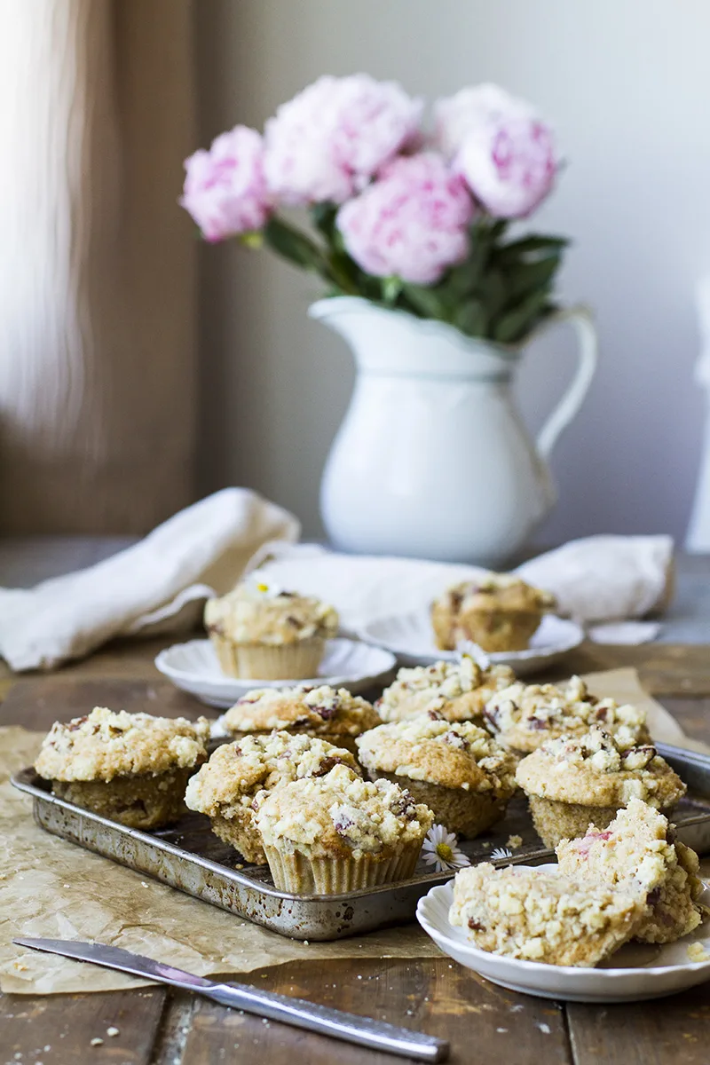 A baking sheet with baked rhubarb muffins, pink peonies in the background.