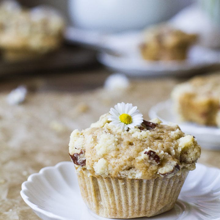 One muffin with crumb topping on a vintage, white plate.