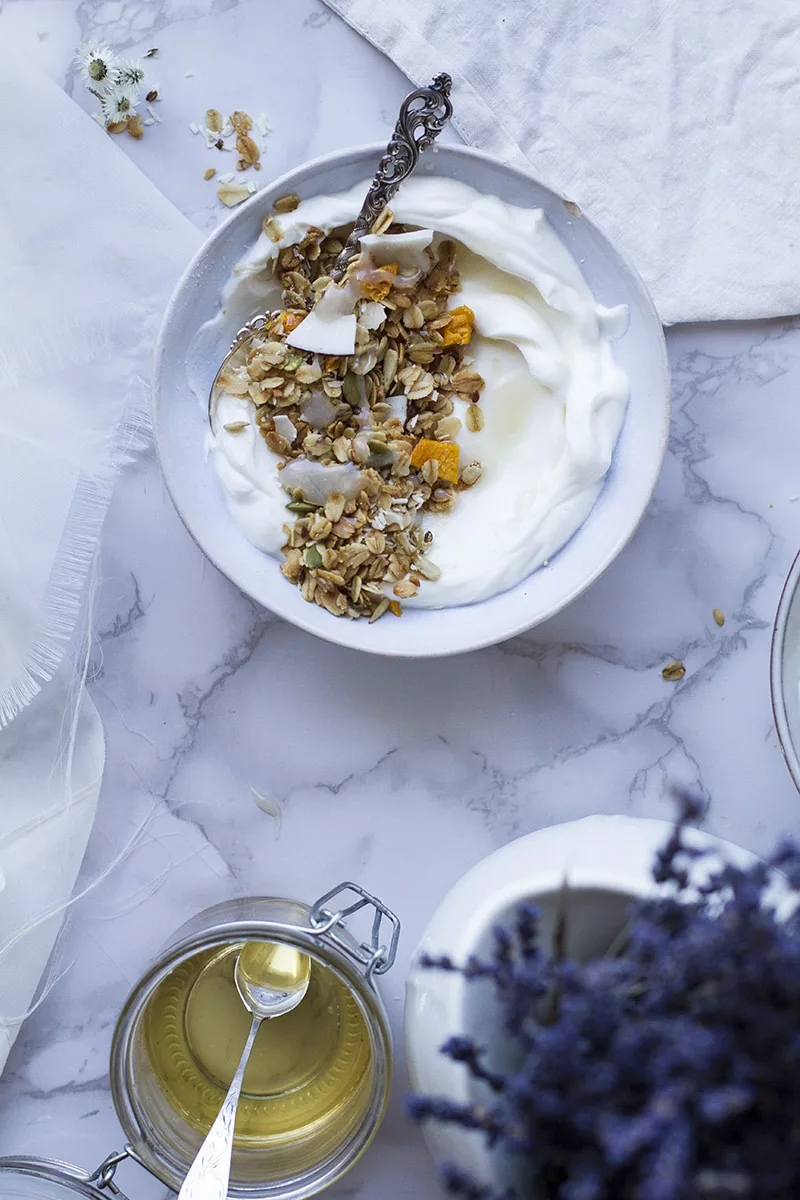 A blue bowl with Greek yogurt and granola, seen from above.