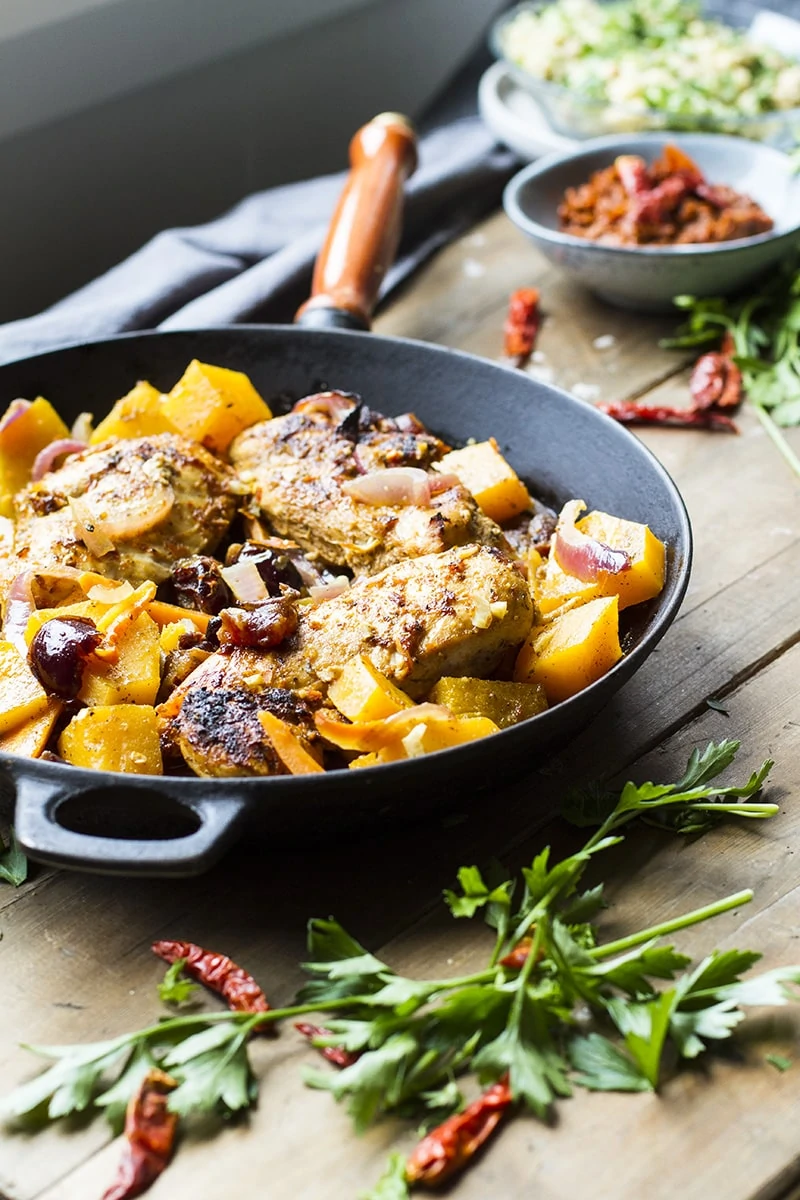 Cast iron skillet with chicken breast and cubed butternut squash.