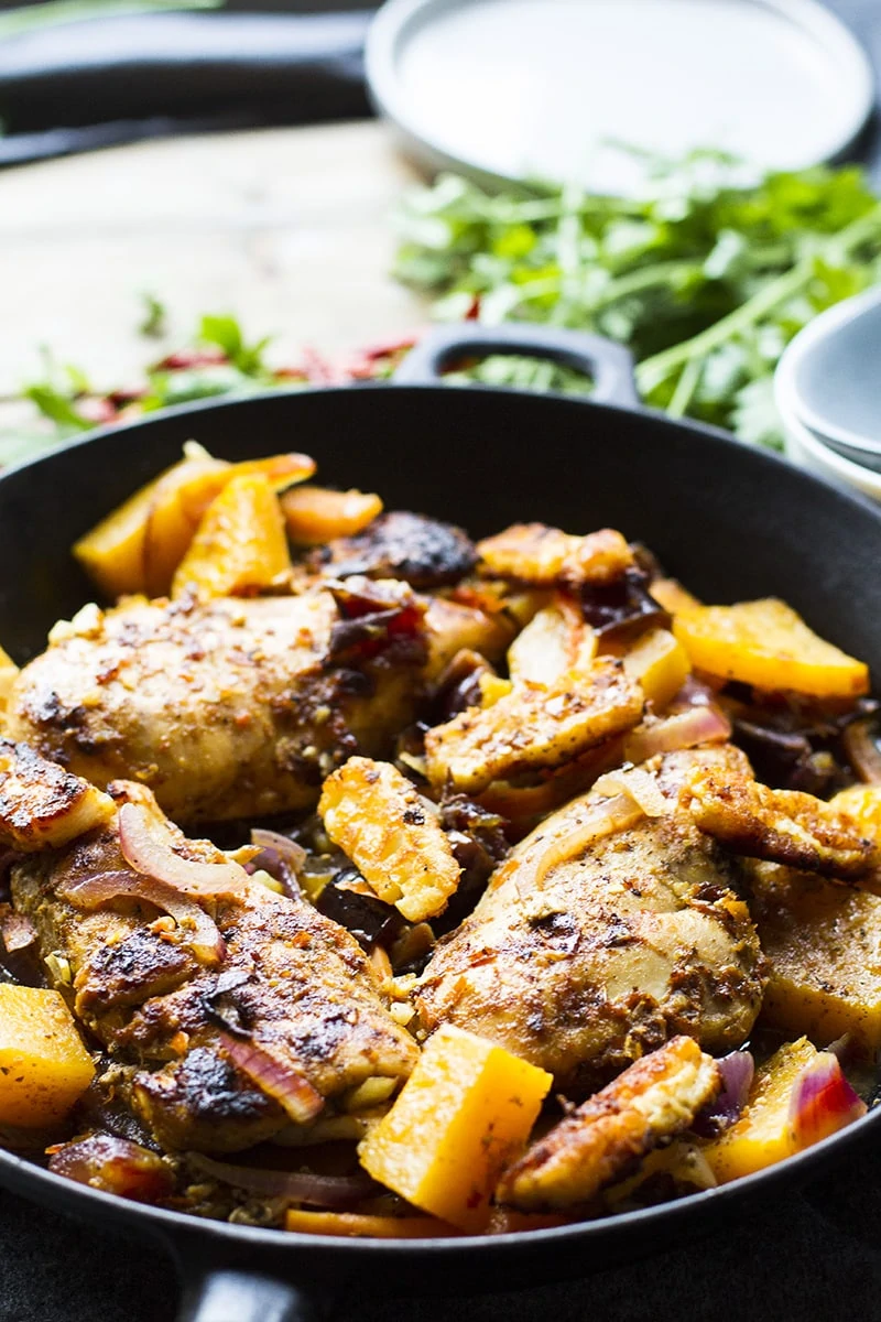 Close-up of the skillet with three chicken breast and cubed butternut squash.
