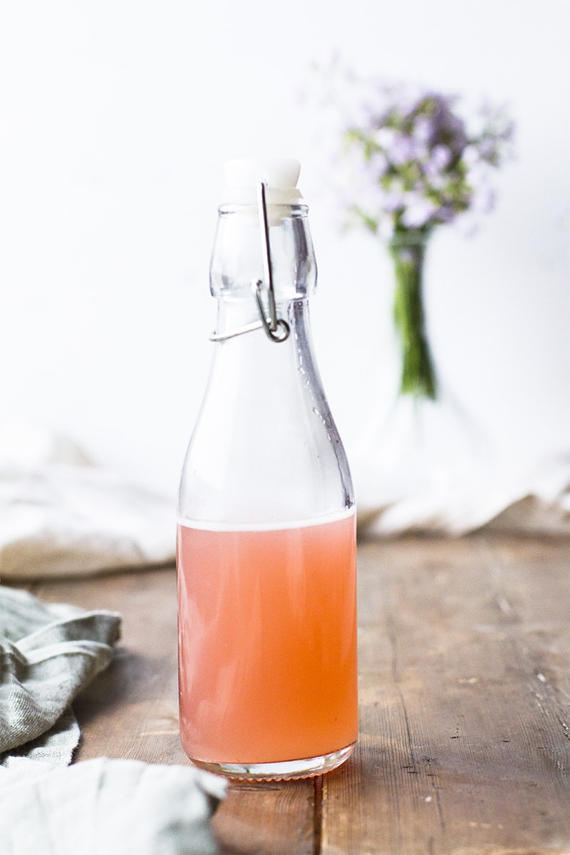 Peach-colored simple syrup in a glass bottle.