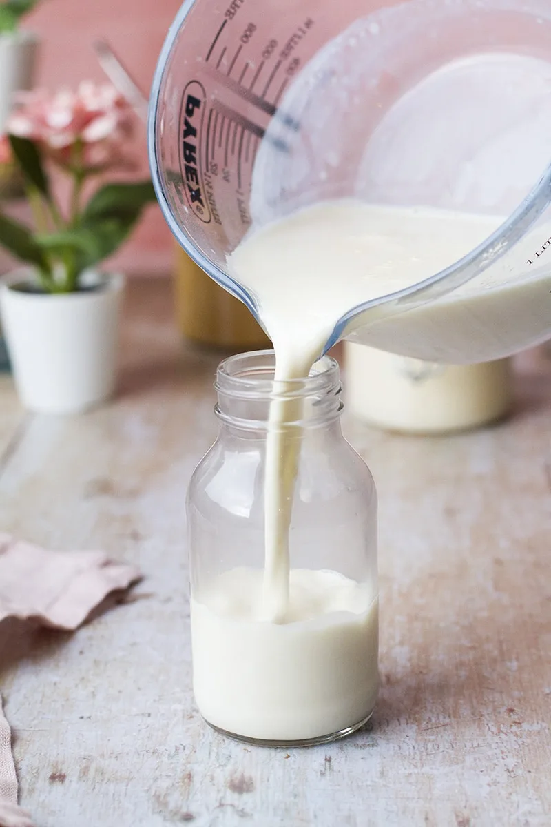 Pouring evaporated milk into a glass bottle.