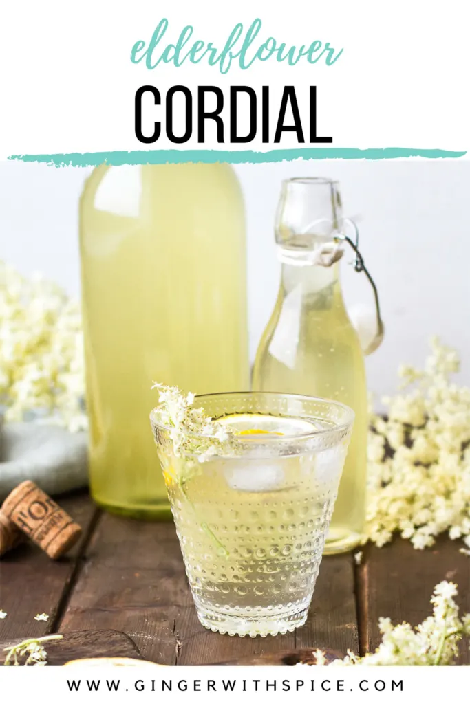 Homemade elderflower cordial in a clear glass with lemon wedge. Pinterest pin.
