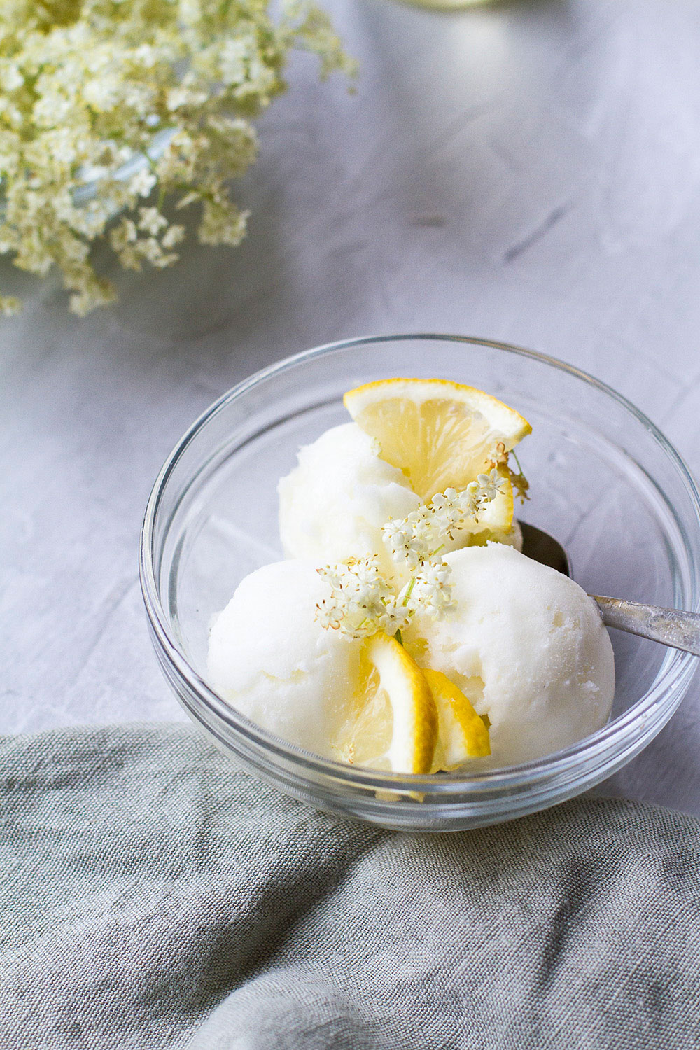 A serving of lemon sorbet in a clear glass bowl.