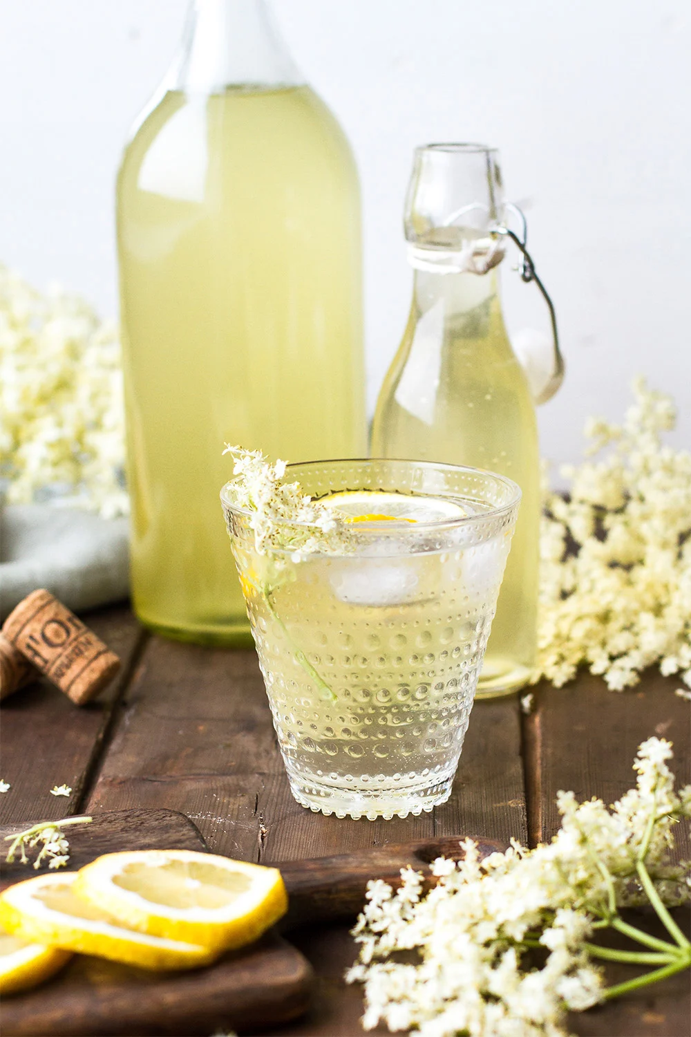 Homemade elderflower cordial in a clear glass with lemon wedge.