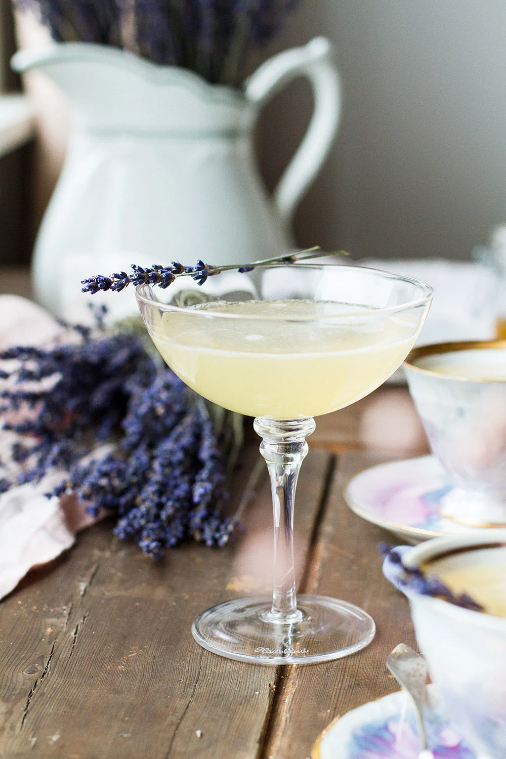 Coupé glass with yellow cocktail, garnished with dried lavender.