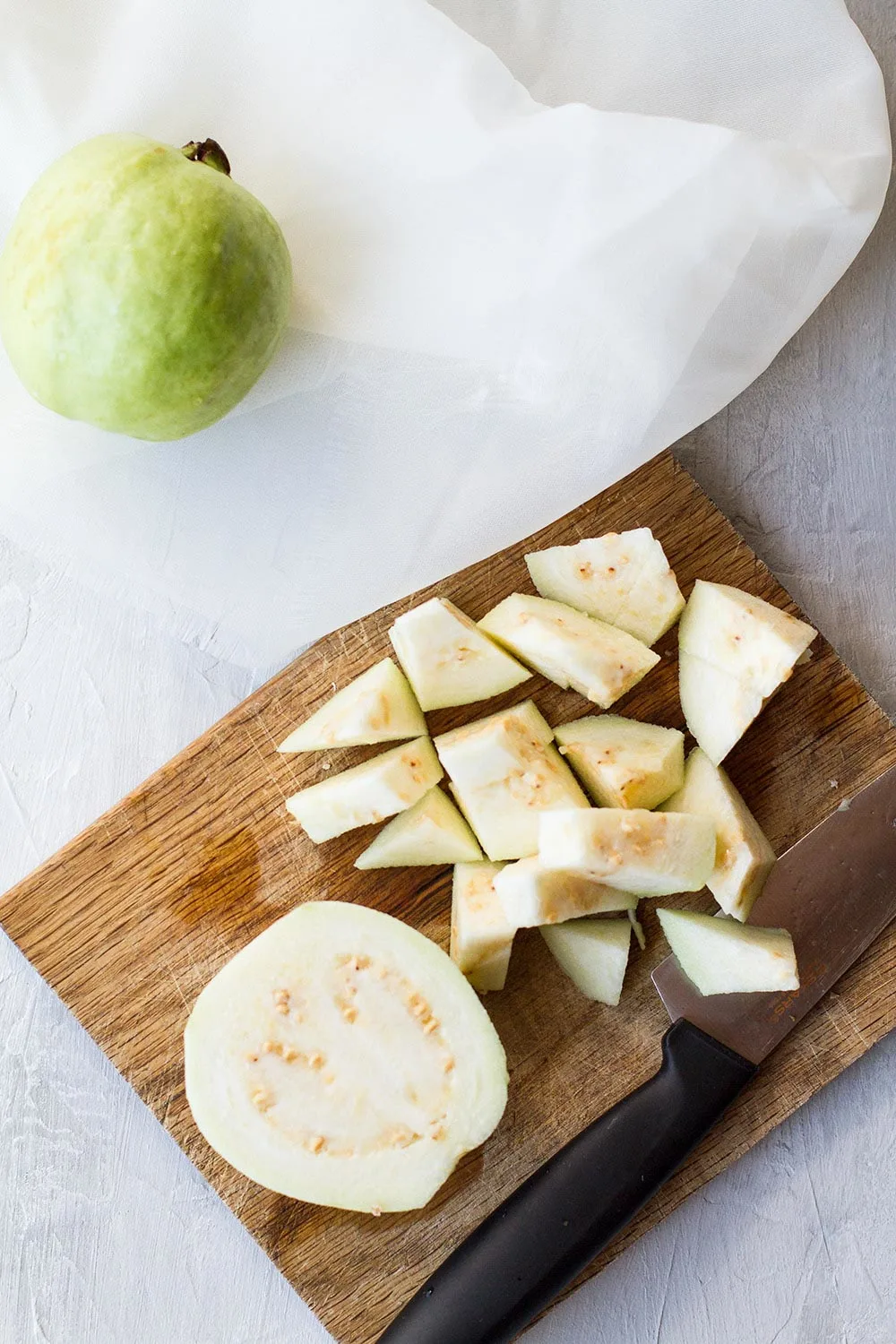 A cutting board with a guava cut open and diced.