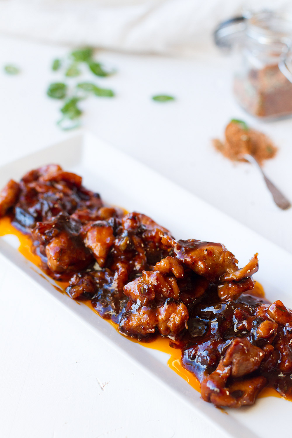 Pork strips on a rectangular plate, in a sweet and spicy sauce.