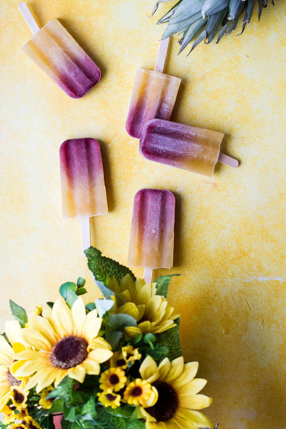 Yellow background with mai tai popsicles and sunflowers.