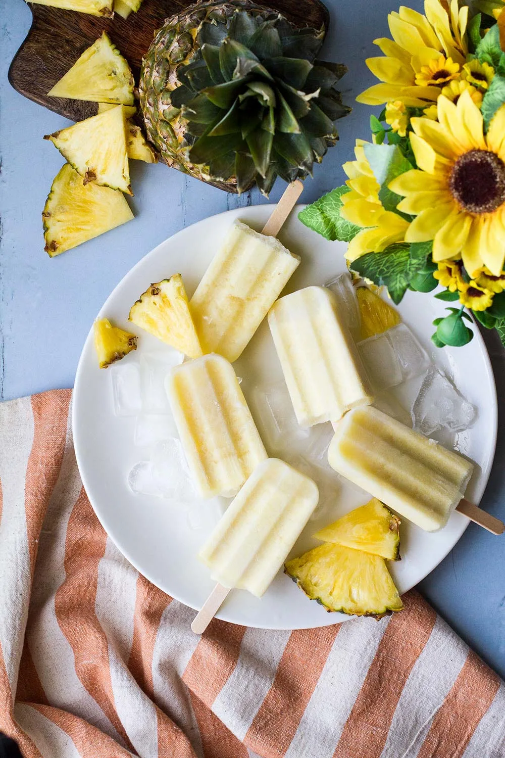 A white plate with pale yellow piña colada popsicles.