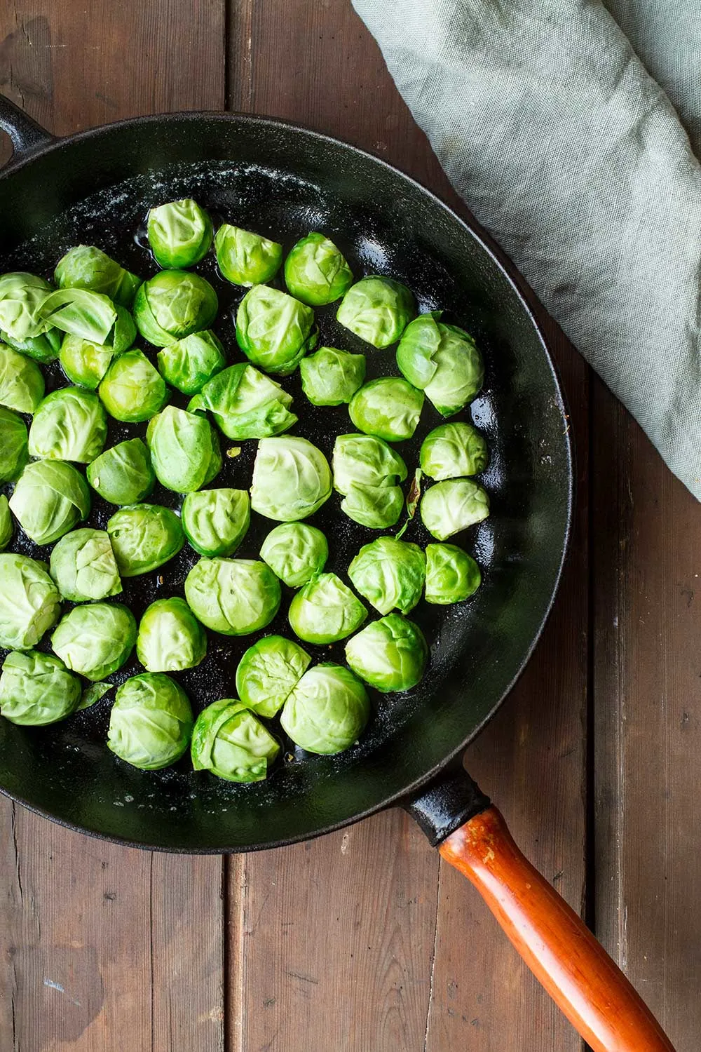Brussels sprouts with cut side down in a cast iron skillet.