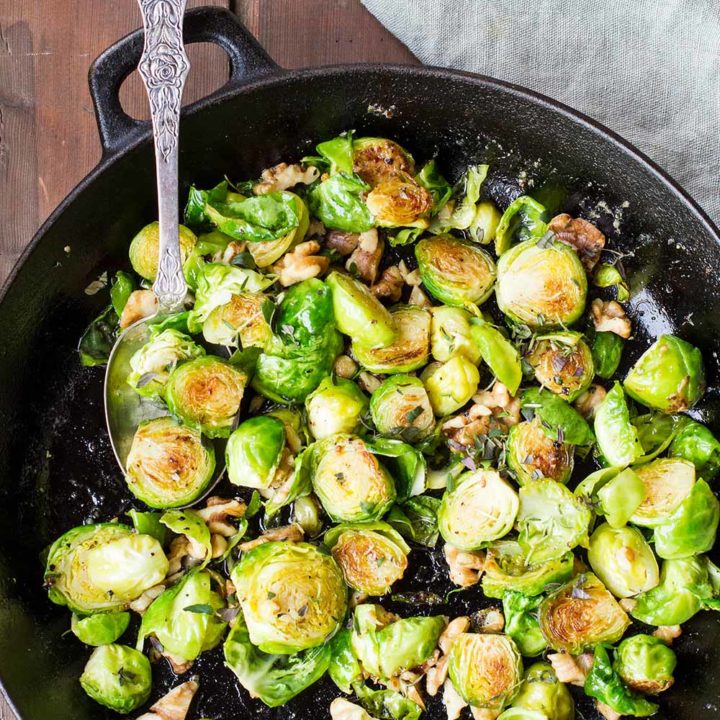 Cast iron skillet with crispy brussels sprouts and a vintage spoon.