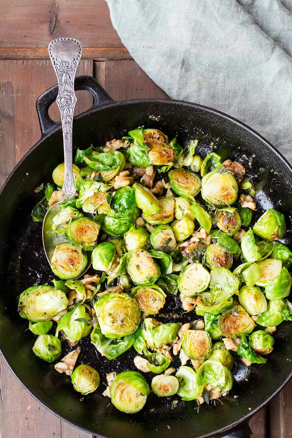 Cast iron skillet with crispy brussels sprouts and a vintage spoon.