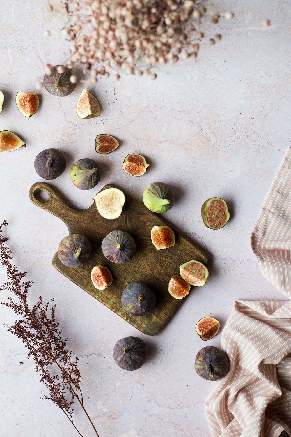 Whole and cut figs on a wooden cutting board. Purple-ish background.