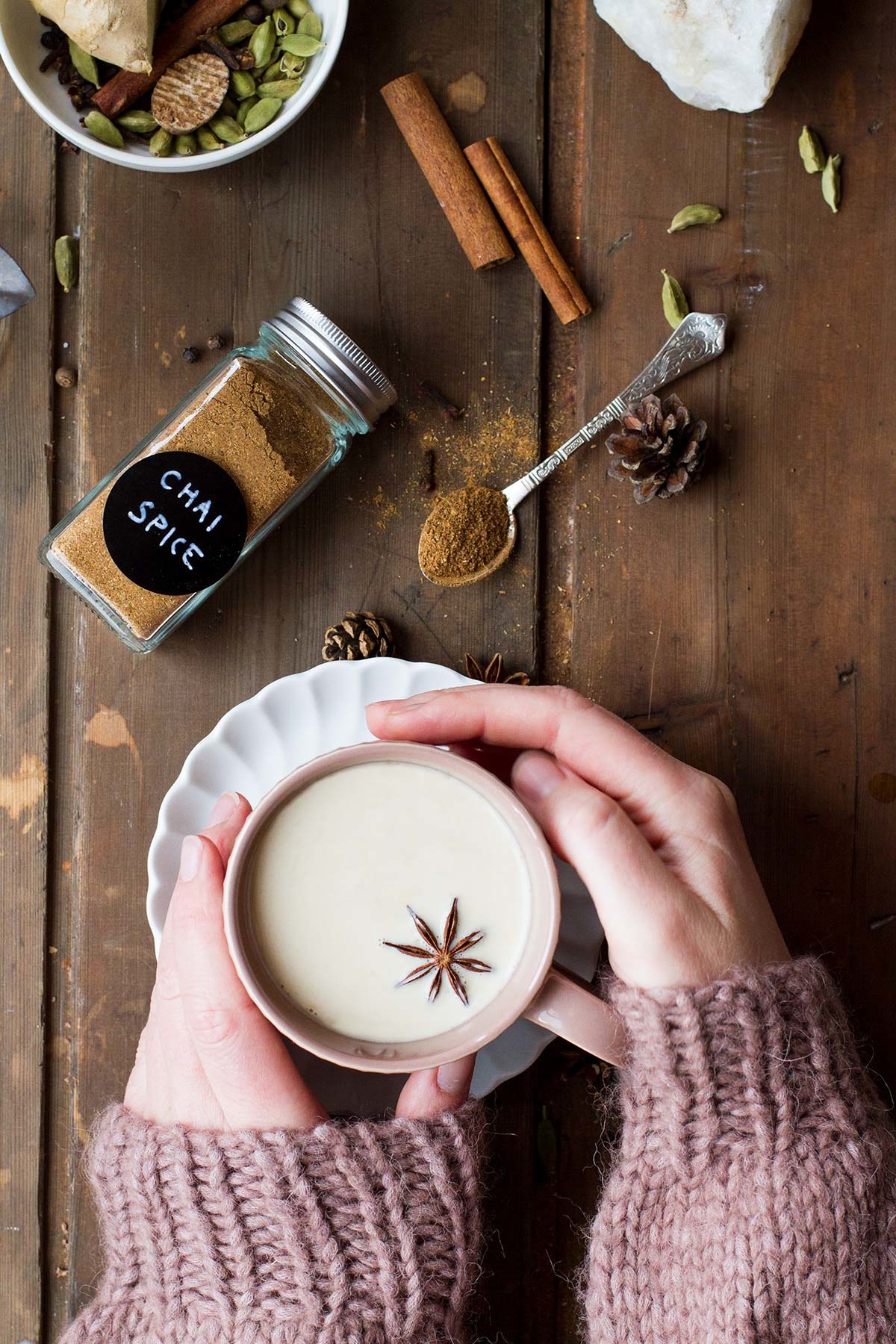 Hands holding a pink mug with chai tea latte.