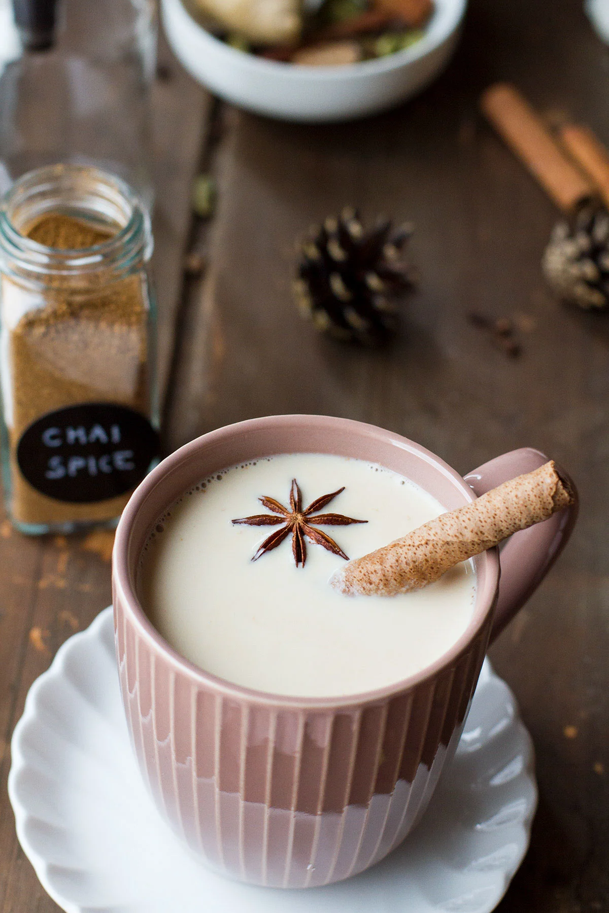 Pink mug with chai latte, garnished with star anise.