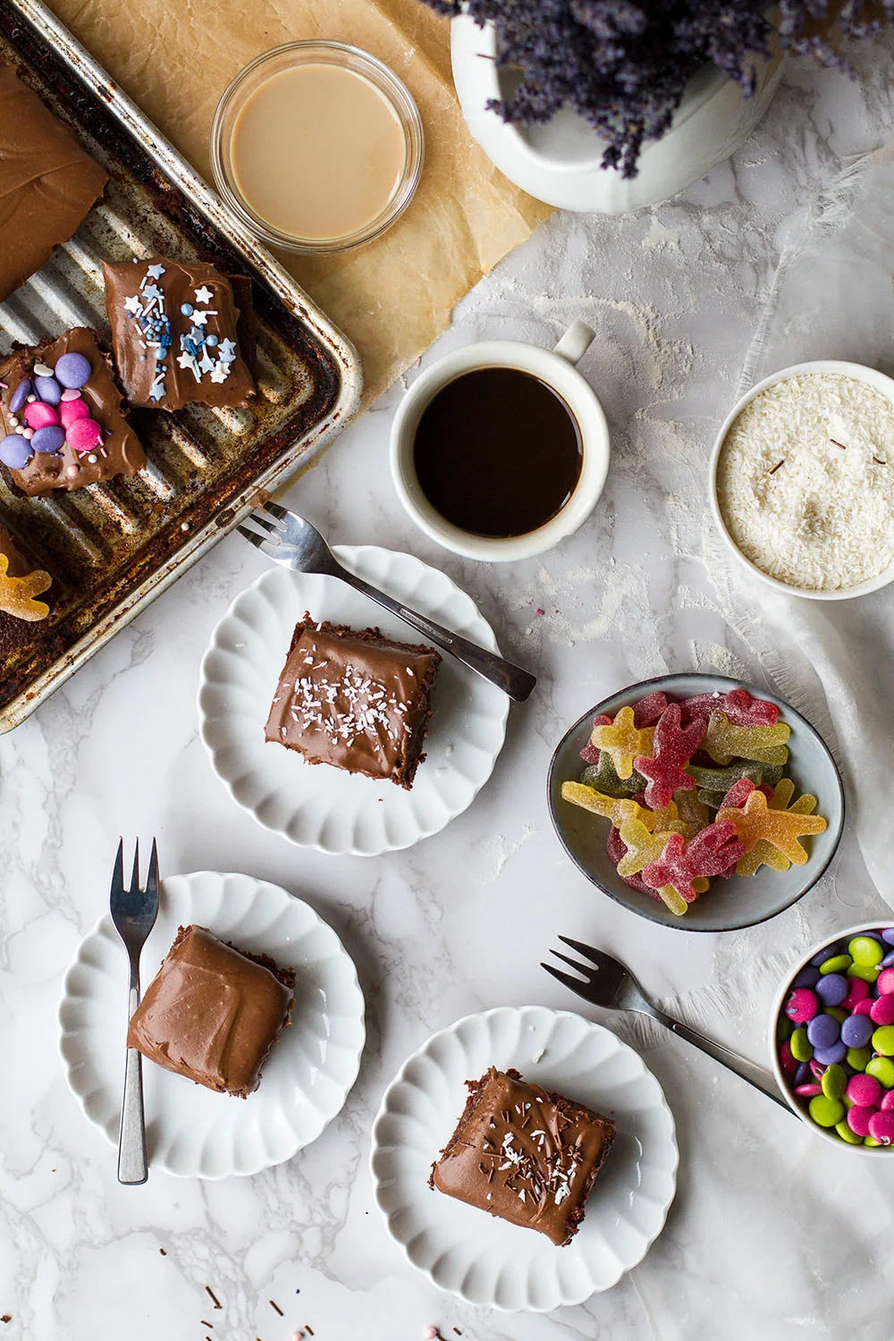 Marble table with several vintage plates with square slices of chocolate cake.