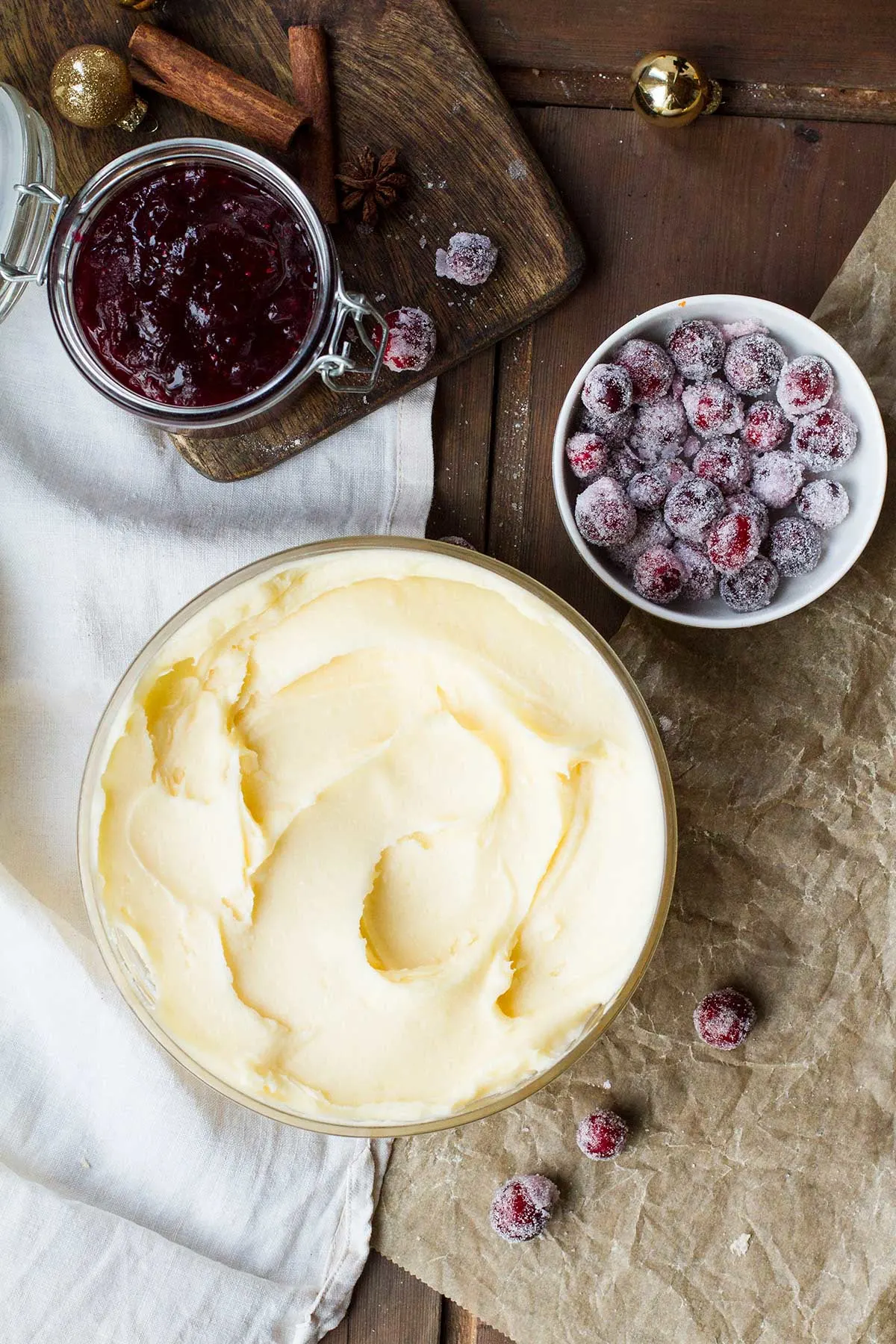 One glass bowl with eggnog icing, one small with sugar cranberries and a glass jar with cranberry sauce.