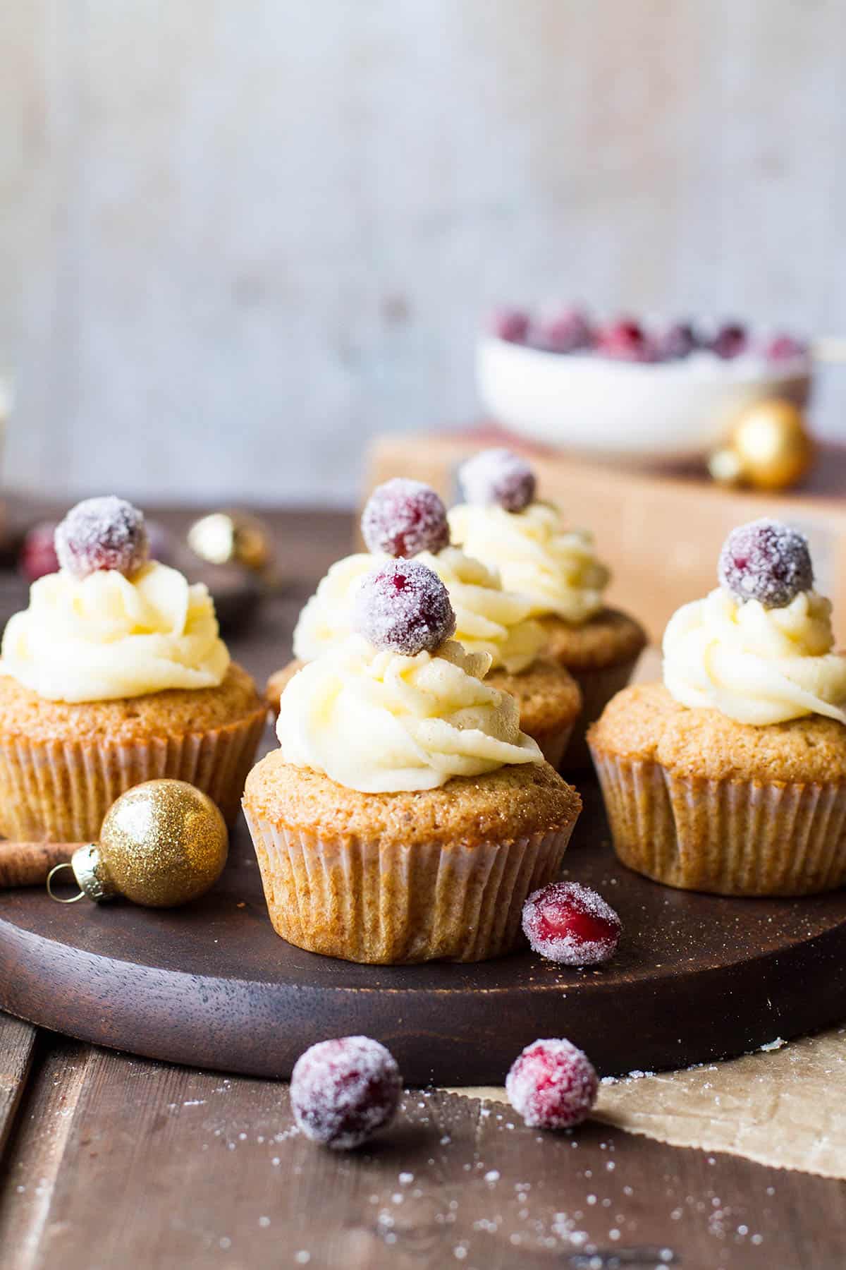 Cupcakes with white icing and sugar cranberry on a wooden plate.