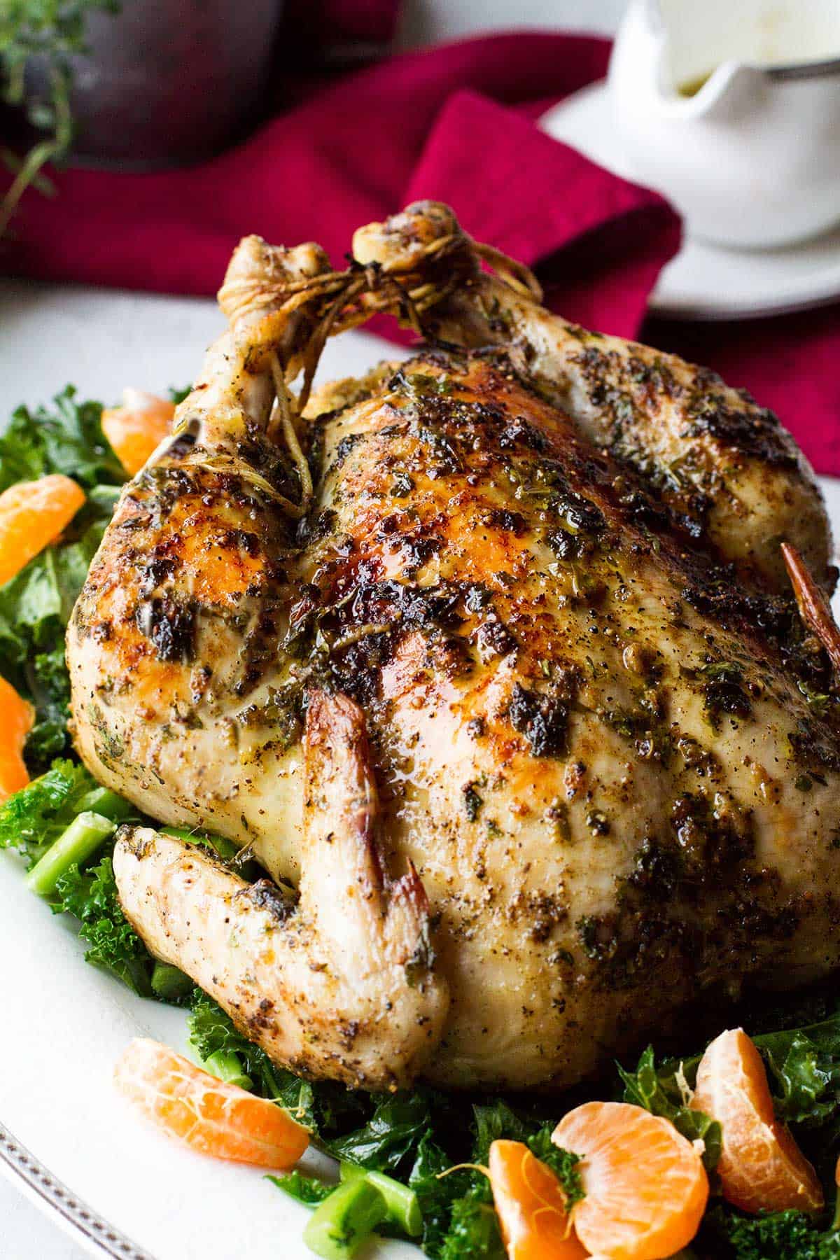 Whole chicken on a plate with kale and clementines.