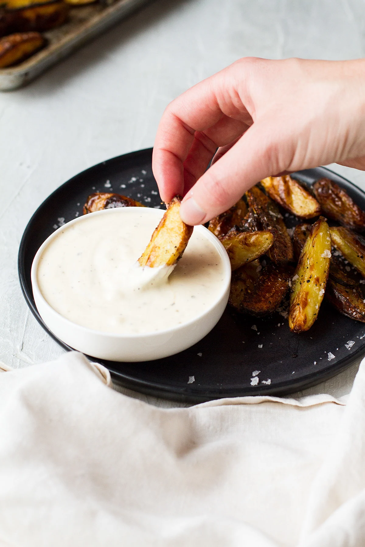 Hand dipping a potato wedge in a pickle dip.