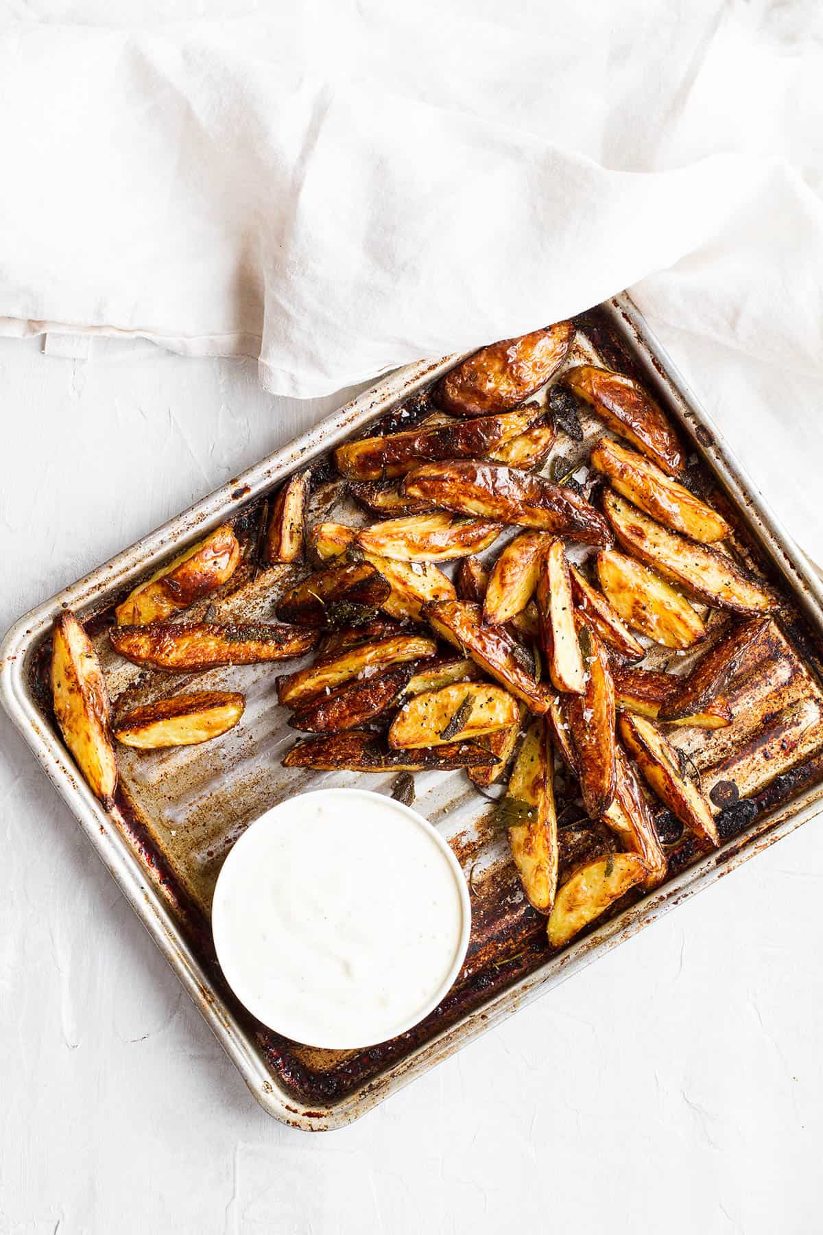 An old baking tray with baked potato wedges, seen from above.