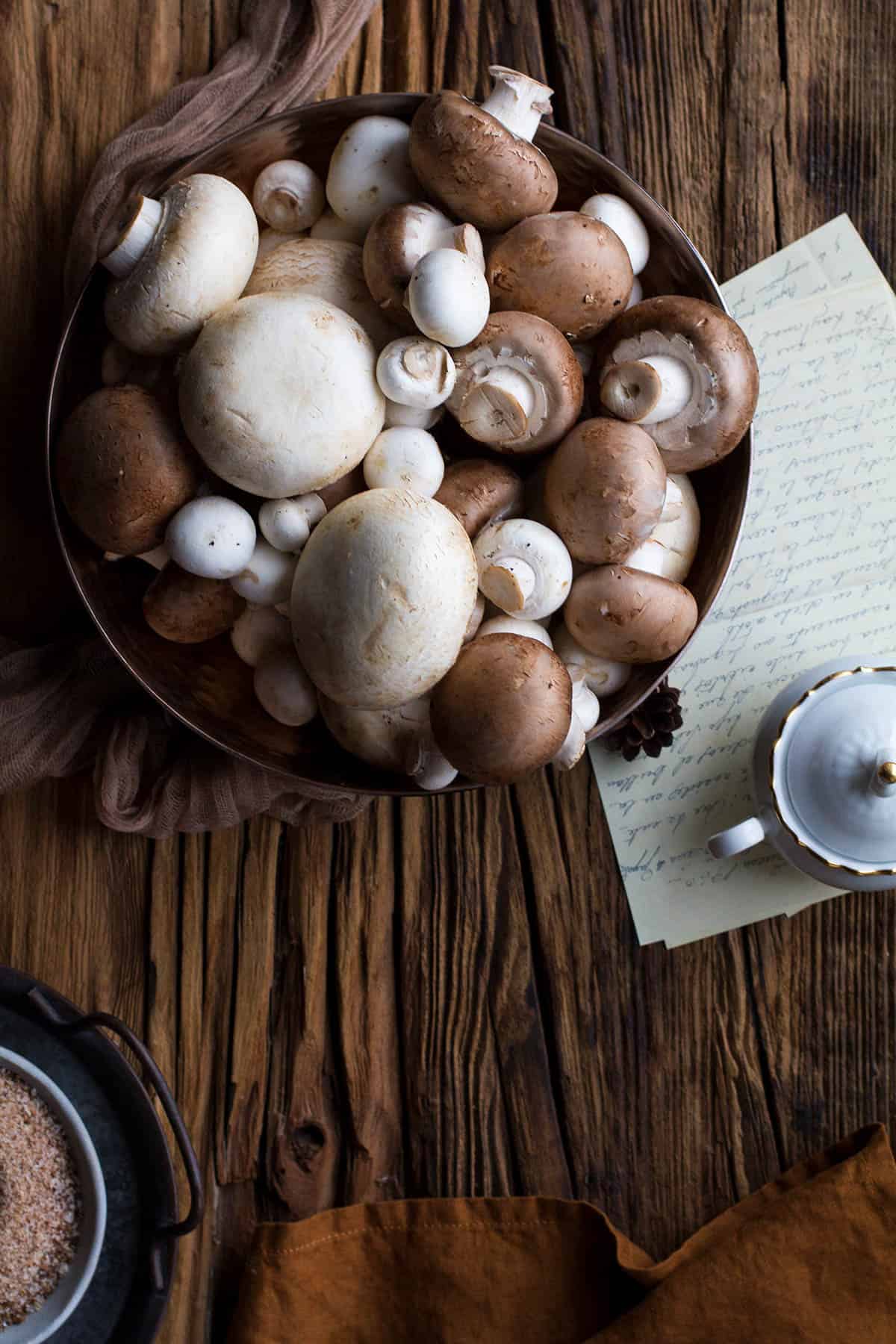 A big bowl with different kinds of mushrooms.
