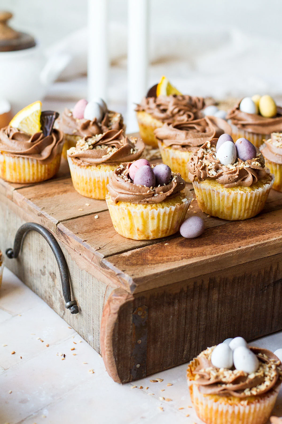 Cupcakes with Easter egg nest decorations on a wooden tray.