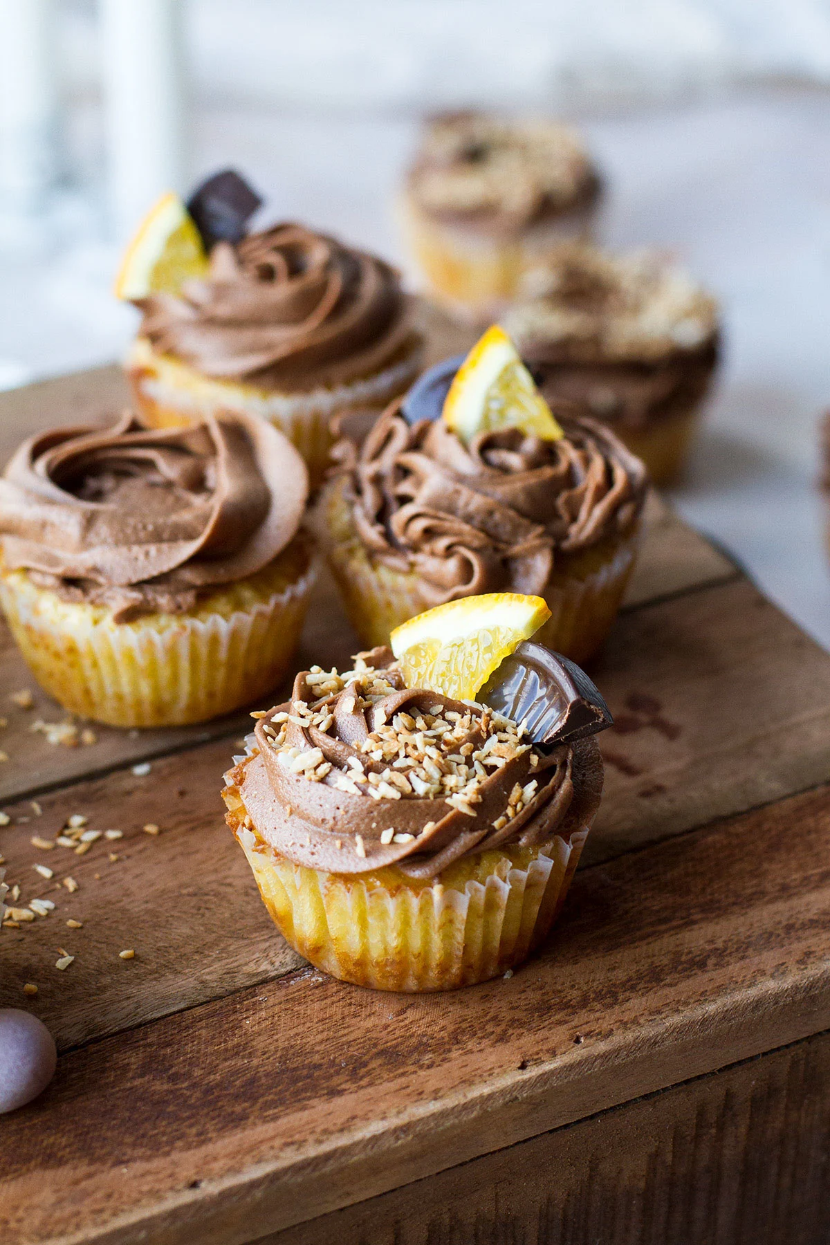 Coconut cupcakes with chocolate buttercream and orange wedge garnishes.