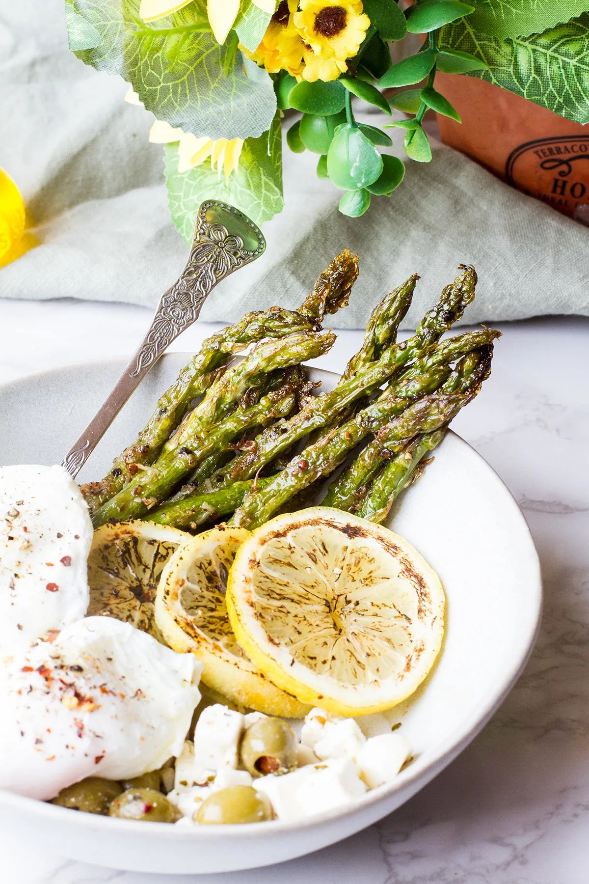Roasted asparagus and poached eggs in a white bowl.
