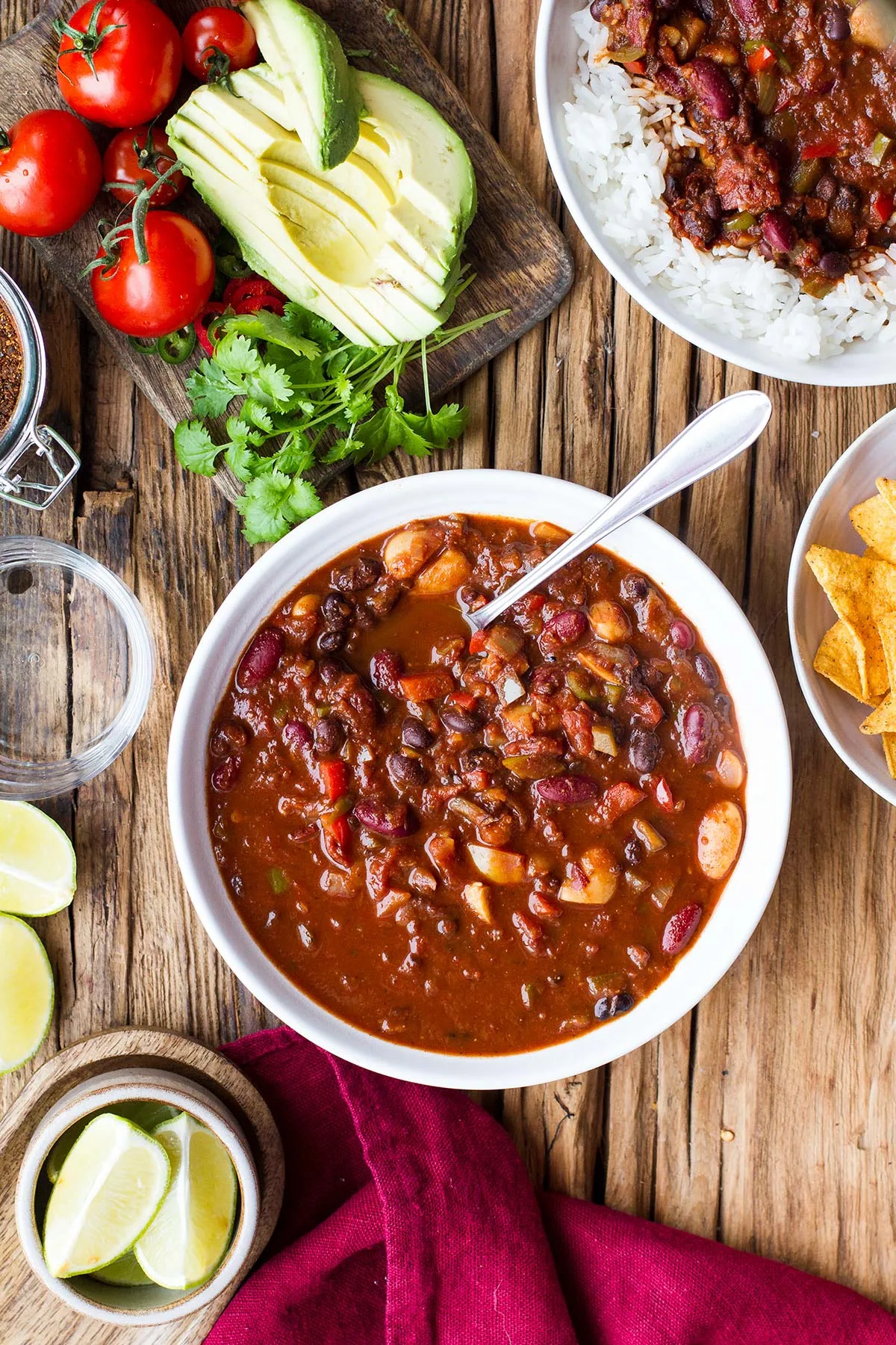 Big bowl of vegan bean chili, optional topping ideas on the side.