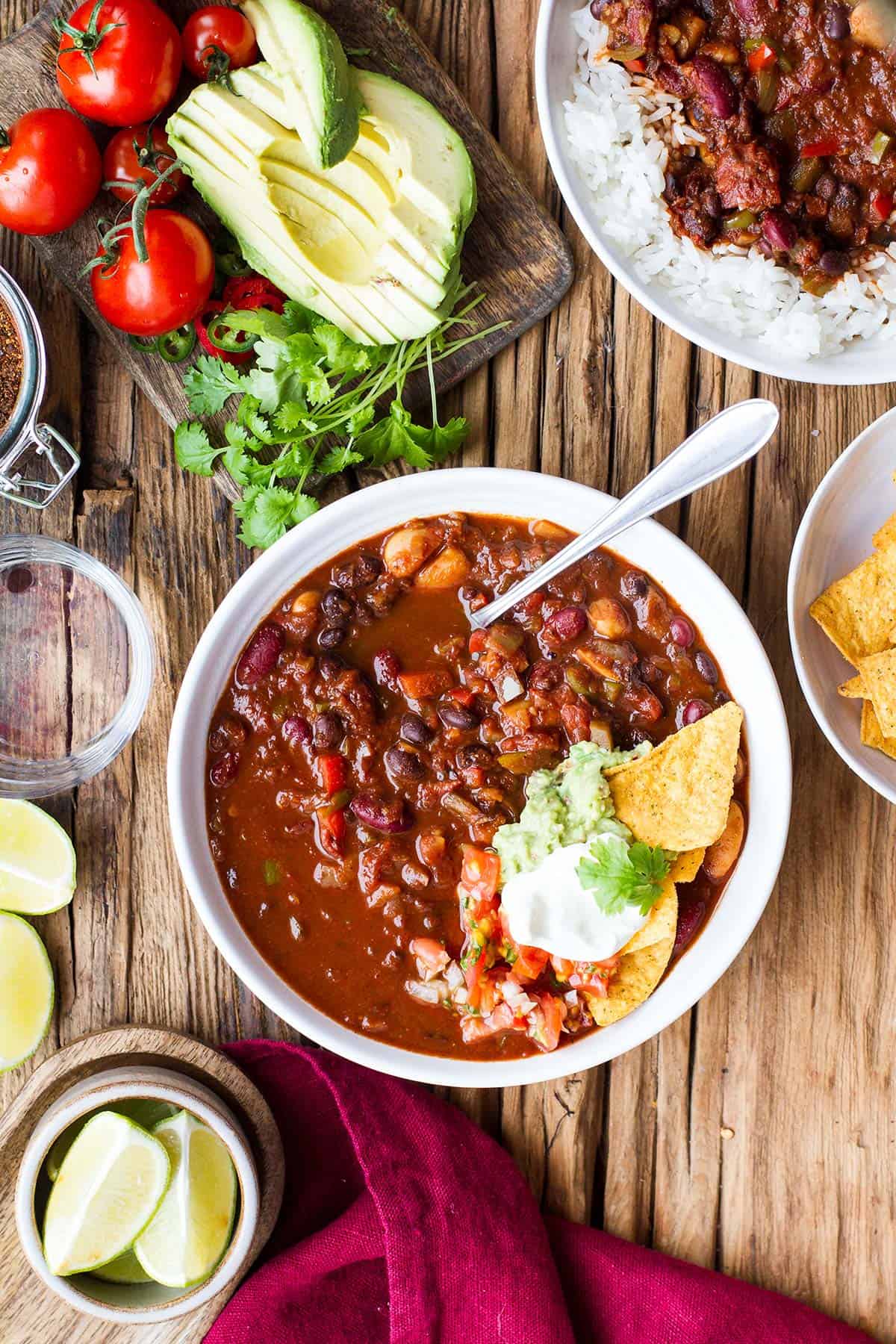 Bowl of vegan chili, topped with sour cream and guacamole.