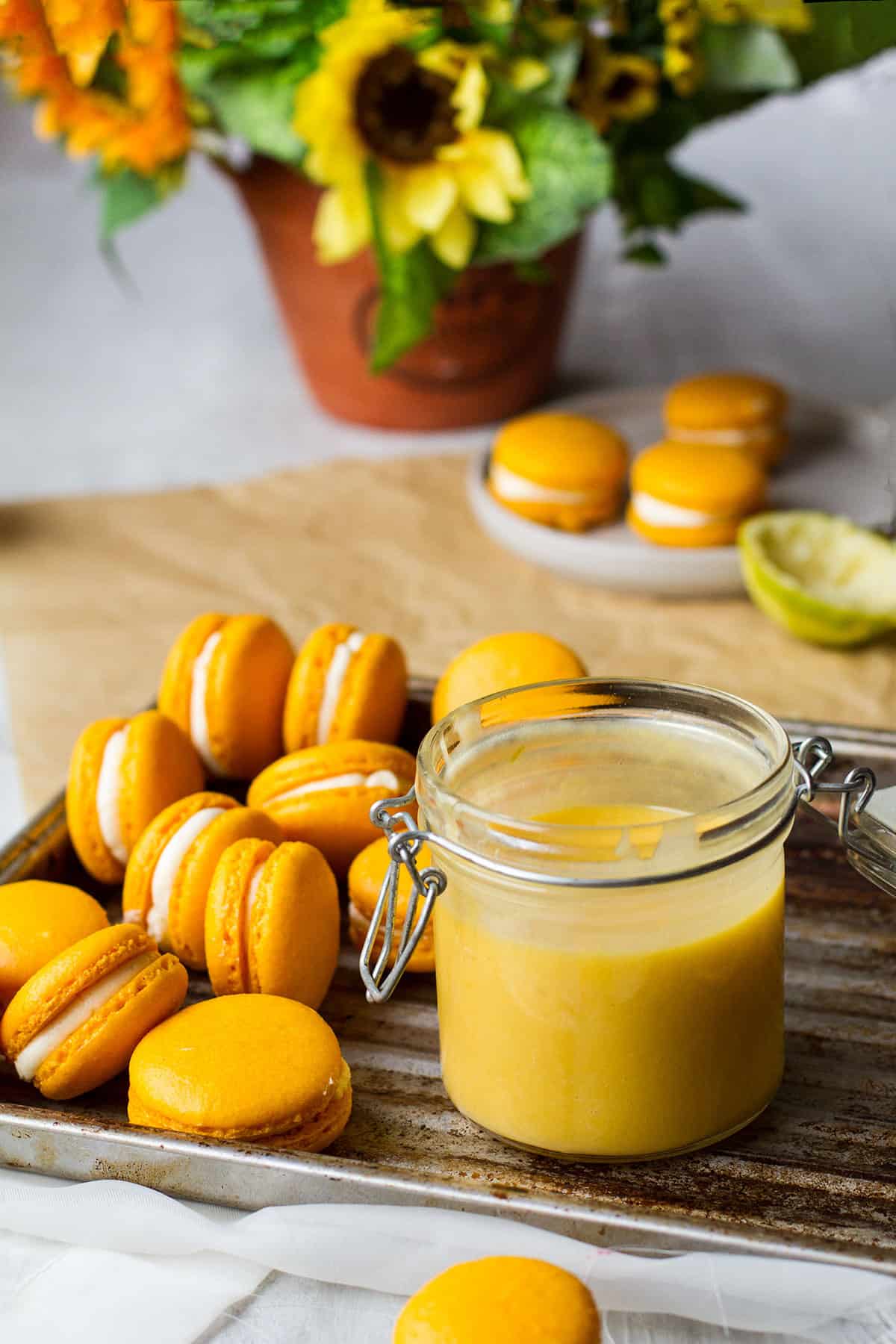 Yellow macarons and mango curd on an old metallic tray.