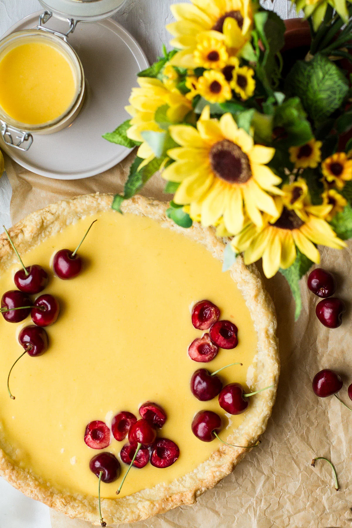 A pie crust with mango curd and cherries.