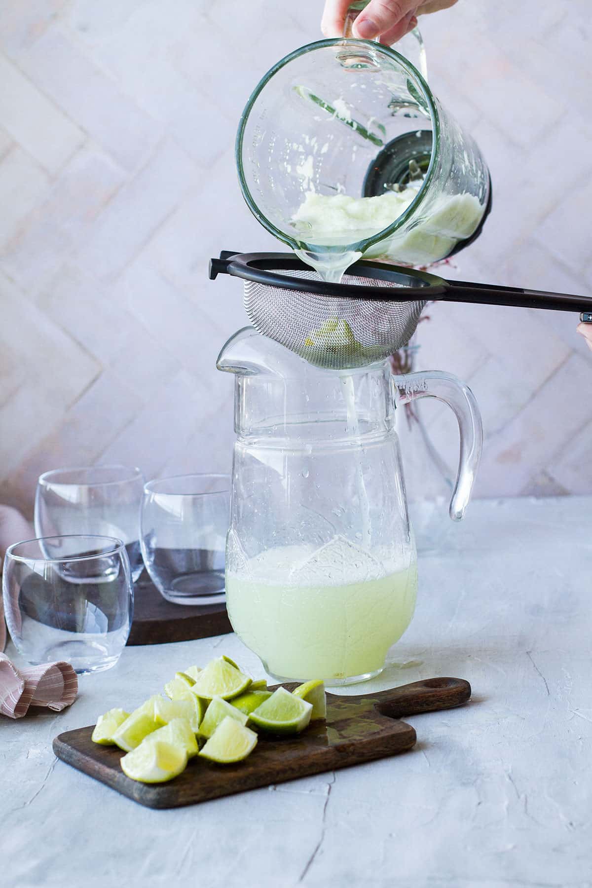 Straining the lemonade into a large pitcher.